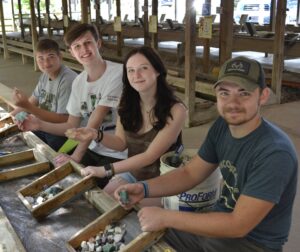 Four smiling visitors to Gem Mountain who are gem hunting