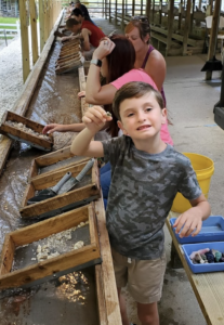 a young child showing off the gemstones he found while flume mining